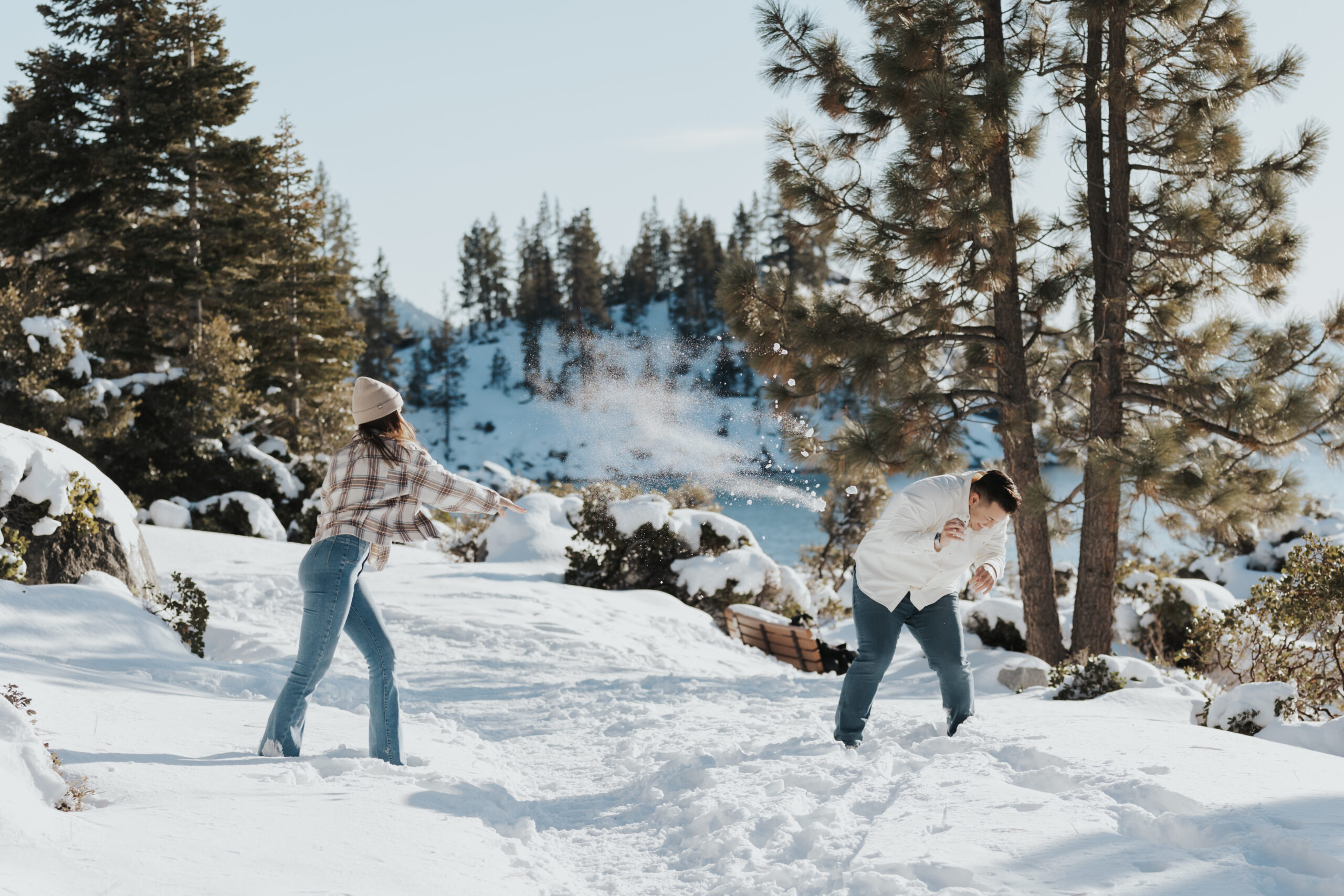 A couple having a playful snowball fight during their engagement photoshoot at Lake Tahoe